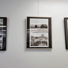 Three monochromatic ink paintings in black frames against a white wall. 