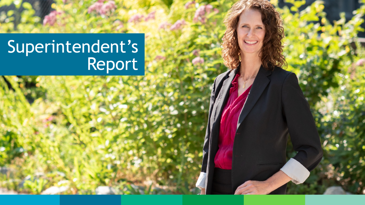 Superintendent Trish Smillie Woman with brown hair standing in front of green bush on a sunny day.