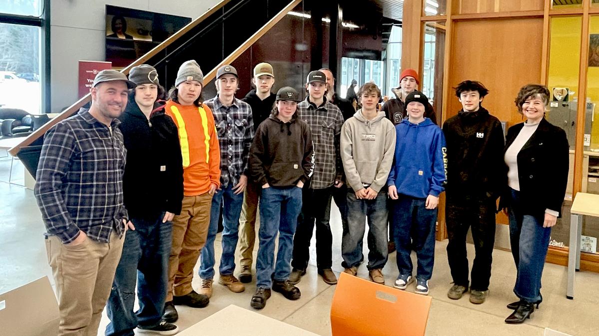 (L to R:) Brent Firkser, Isaiah Thomas, Kayden Boisvert , Oliver Ludwar, Rylan Blais, Rhyder Swetlikoe, Joey Strebchuk, Rob Schwarzer (partially hidden),Sage Novak, Oisin Ward, Kypton Barton, Lee Caldwell, Tamara Malloff A trades teacher stands with a group of teenaged trade students in a college setting.
