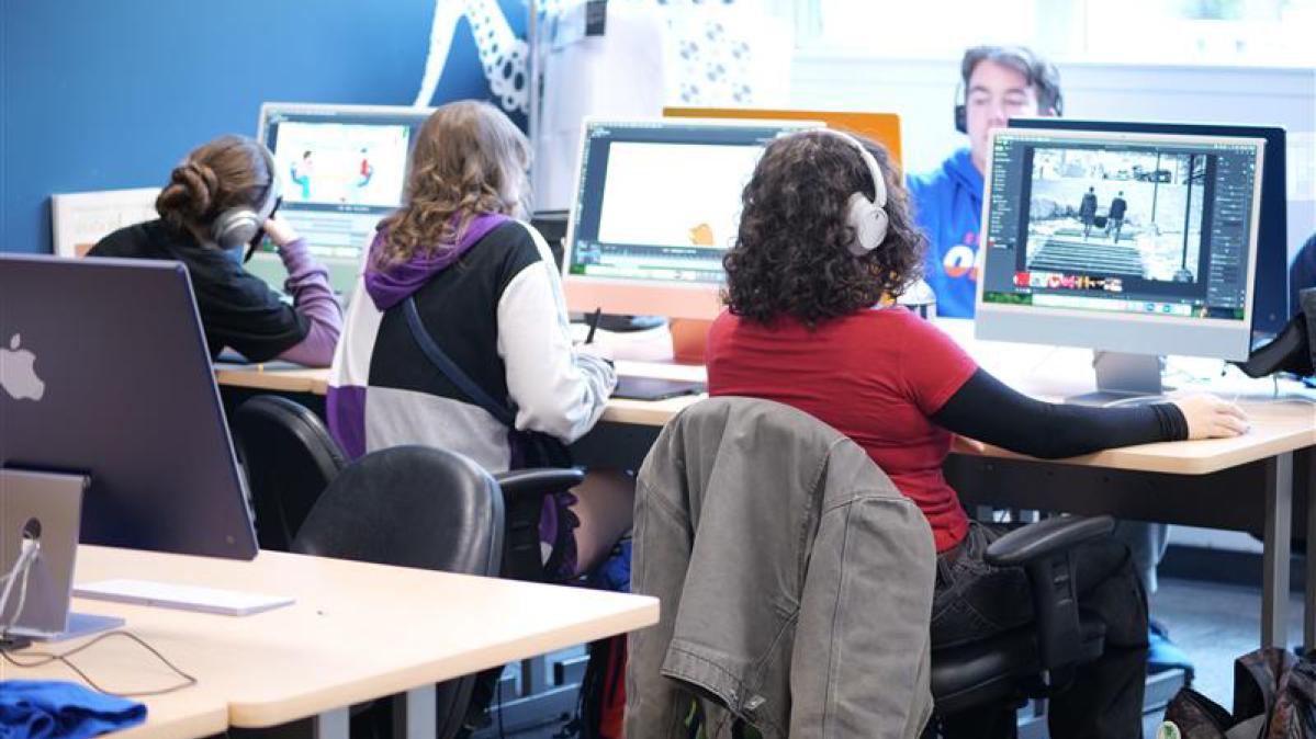 Students seated at desktop computers in a classroom.