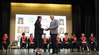 High school graduate receives diploma from official on stage