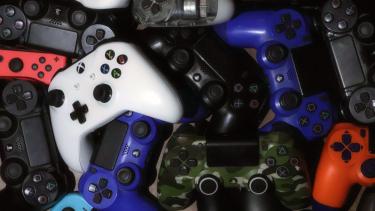 Black, white, blue, light blue and camo game controllers jumbled in a pile
