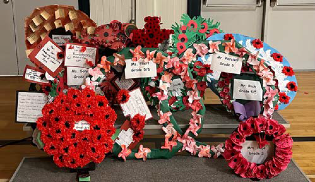 Wreaths of red poppies and colourful flowers on grey dais on gymnasium floor