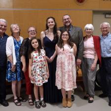 A multi-generational family poses together in a school gymnasium.