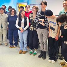 Students stand in front of a classroom with one student holding a glass award that others peer at.