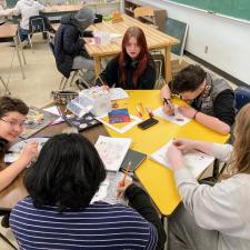 Group of middle school students work on art at a round table