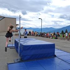 A female athlete in mid-air of a high jump competition outdoors in a paved school area
